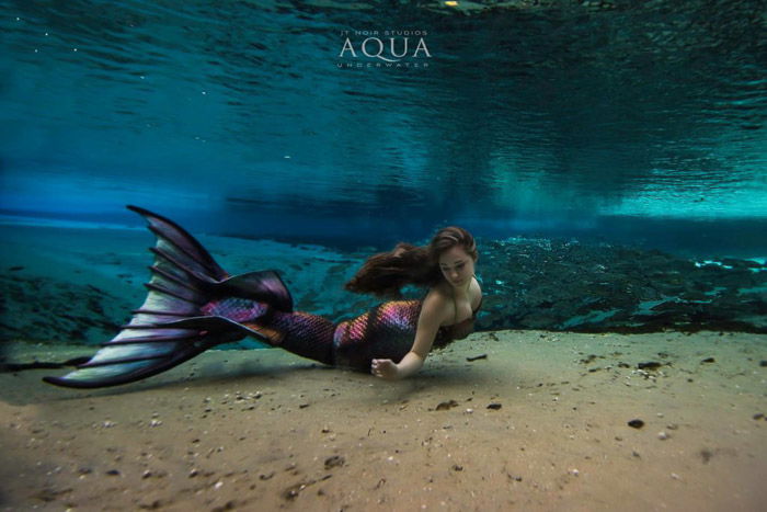 Dreamy underwater portrait of a female model with brightly colored mermaid tail 