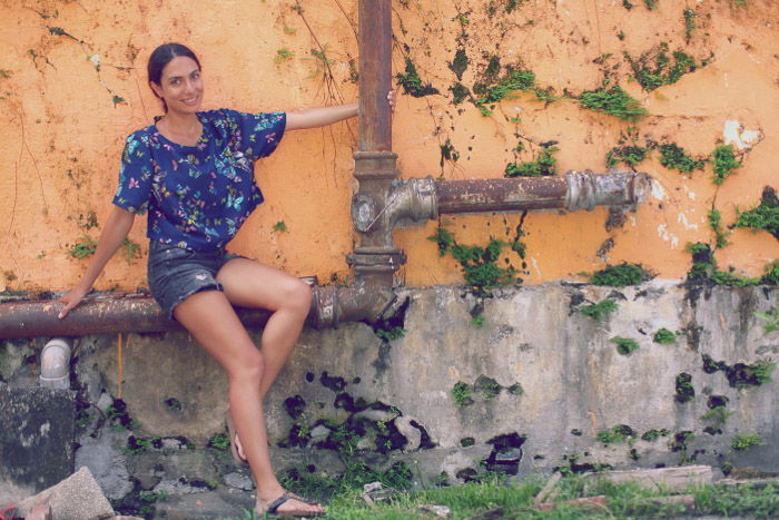 Urban portrait of a female model posing on metal pipes by a stone wall