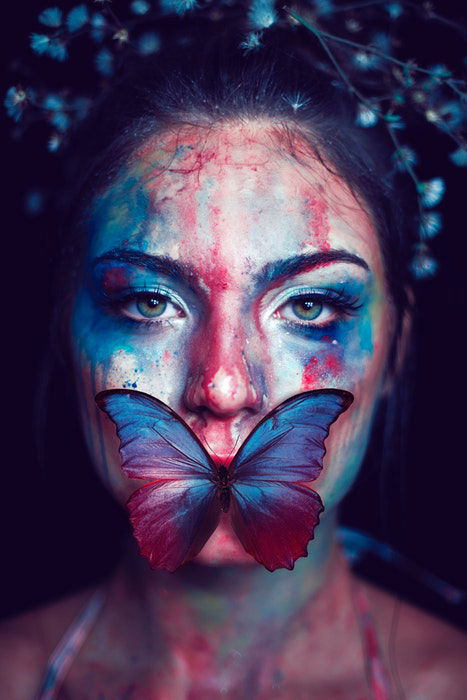 Woman with painted face and a butterfly on her mouth 