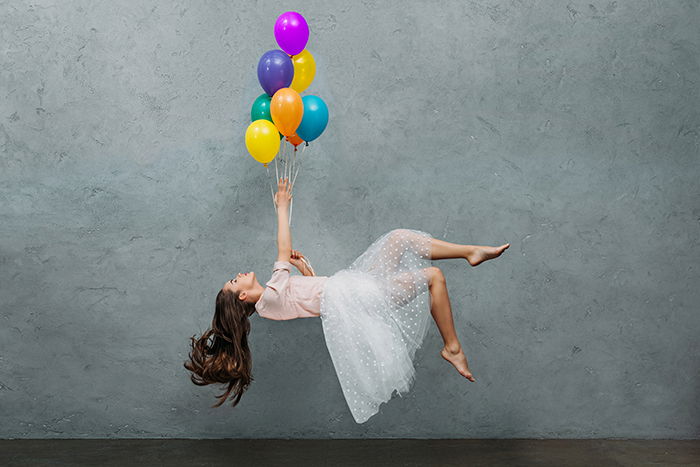 Young woman levitating with ballons.