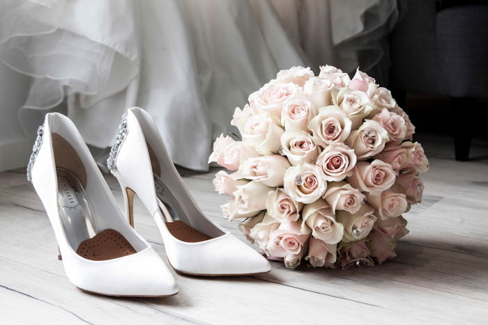 Artistic still life of a wedding bouquet and shoes on wooden floorboards - fine art wedding photography 