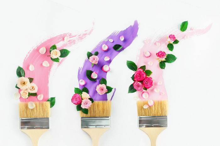 A minimalist flat lay with brushes covered with different types of newborn flowers as an example for spring photography ideas