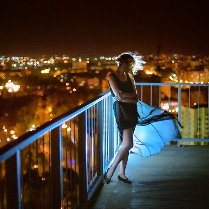 Stunning portrait of a female model posing on a balcony at night shot with a speedlight