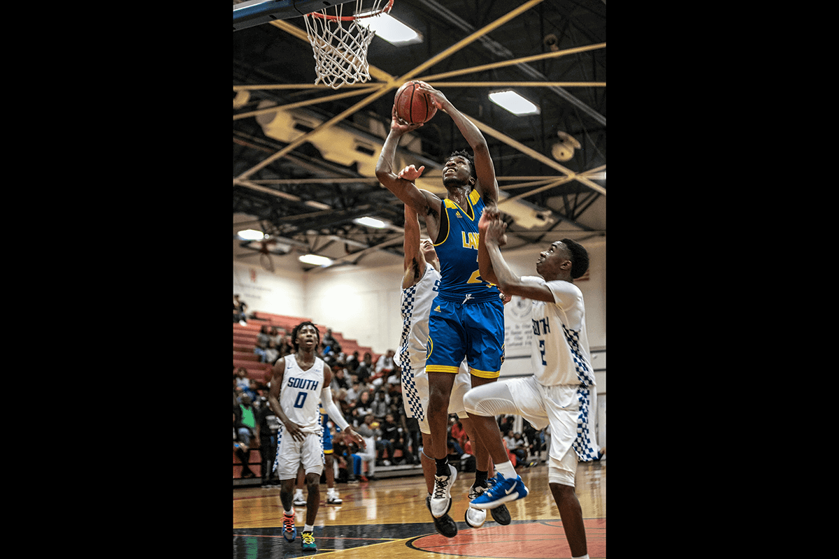 A player going for a layup in a game surrounded by opposition players as an example of basketball photography