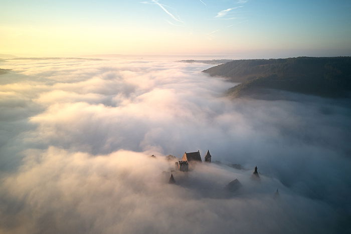 aerial photo of a castle submerged in mist - beautiful photography principles