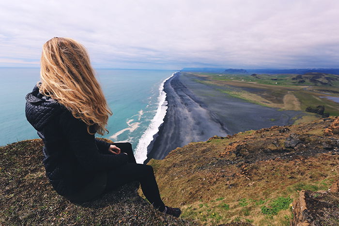 a woman sitting on a cliff overlooking a beautiful coastal landscape - beautiful photography principles