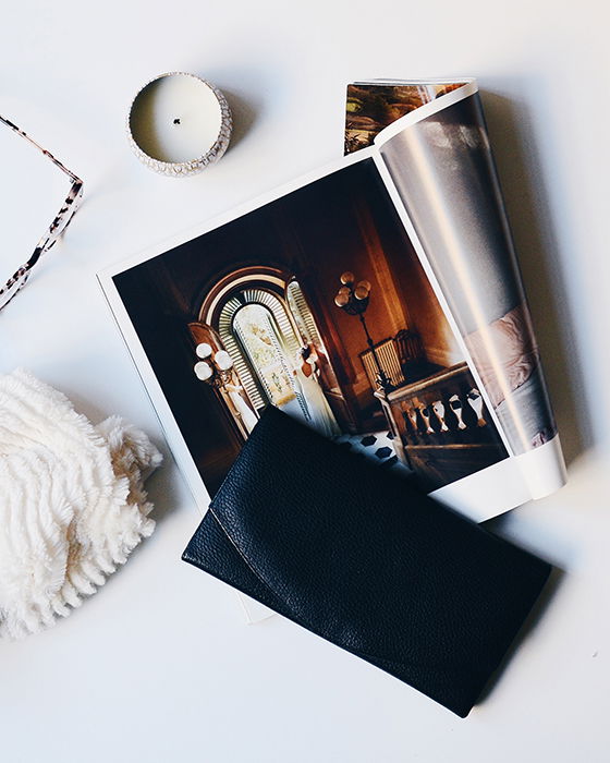 An artistic flatlay of a full-page photobook, a candle, glasses and a wallet on a white table - how to make your own photo book to make your own photo book