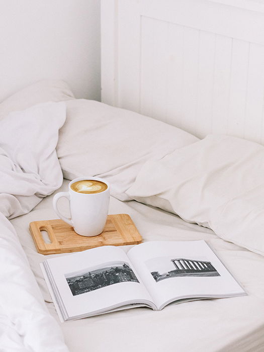 An artistic still life of a photobook and a cup of coffee on a bed - how to make your own photo book to make your own photo book