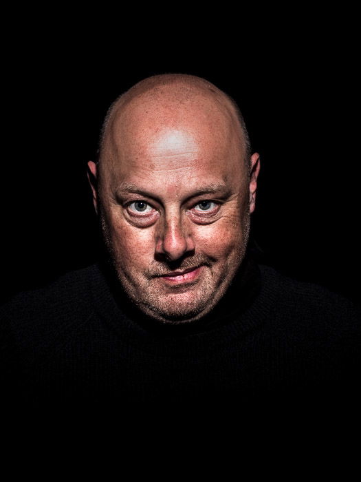 A studio portrait of a male model shot with Butterfly light which creates a short shadow below the nose. short and broad lighting techniques