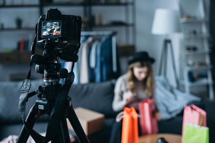 A DSLR camera set up on a tripod to take a portrait of a female model 