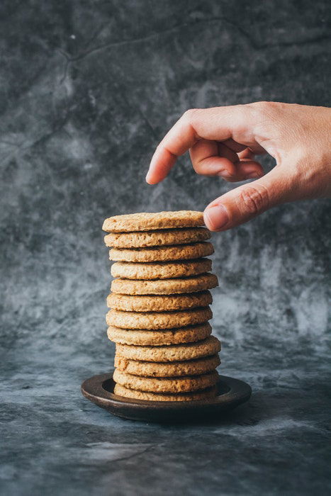 A persons hand above a stack of cookies.