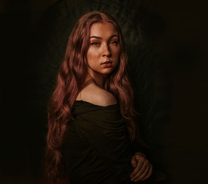 Atmospheric portrait of a moody female model posing against a black background - examples of dark portraits