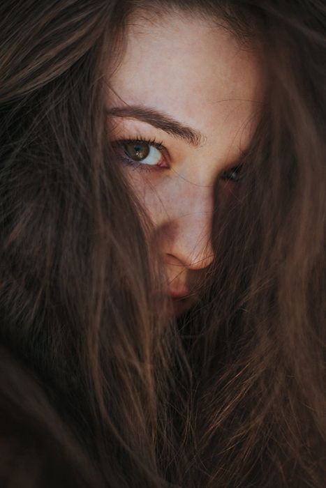 Atmospheric close up portrait of a moody female model with hair covering her face - examples of dark portraits