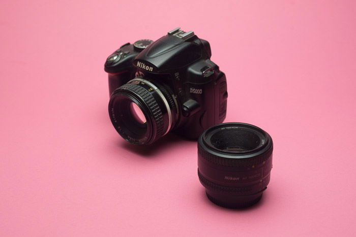 A Nikon DSLR lens on baby pink background 