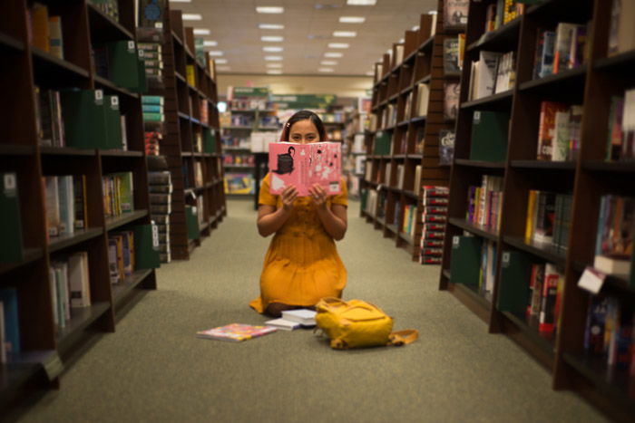 Conceptual portrait of a girl reading on a library floor shot using freelensing photography