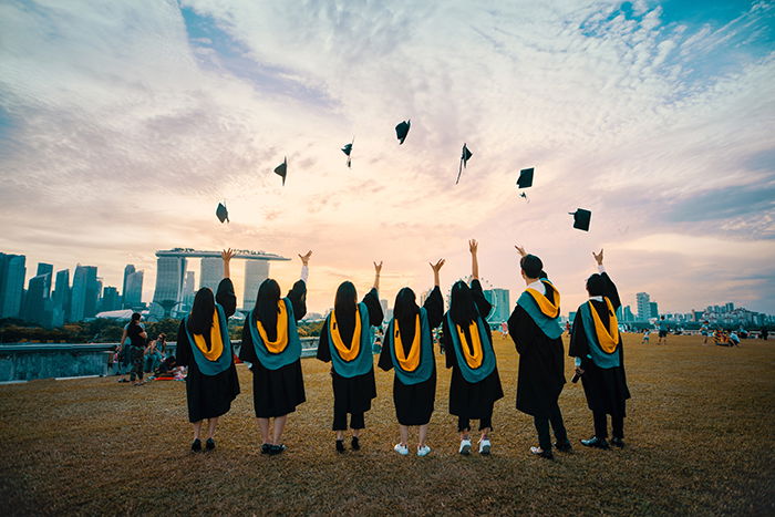 A group of graduation students tossing their hats in the air - graduation photography