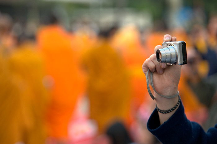 A person holding a compact camera against a blurry background - grey market cameras