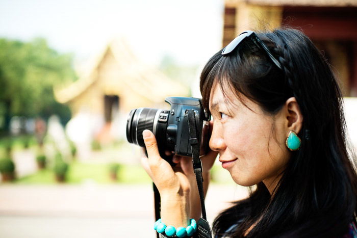 A female photographer holding a compact camera against a blurry background - grey market cameras