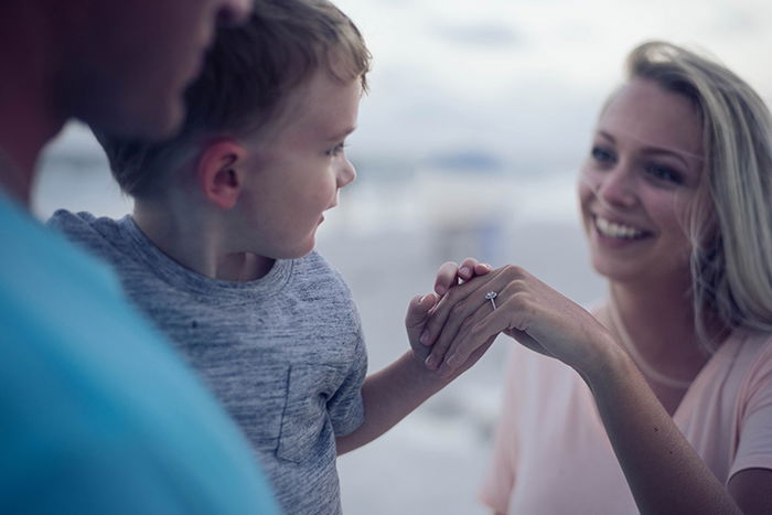 A candid shot of a father holding a young boy towards his smiling mother - lifestyle portraits