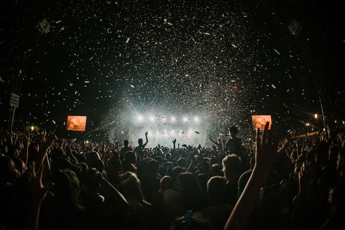 a large crowd watching a concert in low light - music festival photography tips