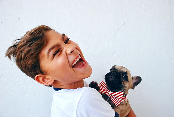 Fun portrait of a laughing young boy holding a small dog - smiling people