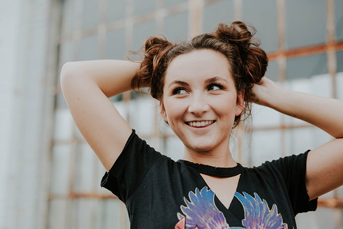 A woman holding her hair up and smiling while looking upwards.