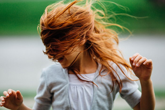 Fun portrait of a laughing female model tossing her auburn hair - how to smile for pictures