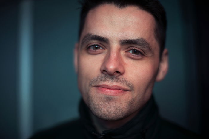 A portrait of a dark haired man smiling natural