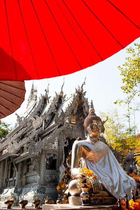  A statue of buddha under a red umbrella in front of a temple - how to remove glare in photos