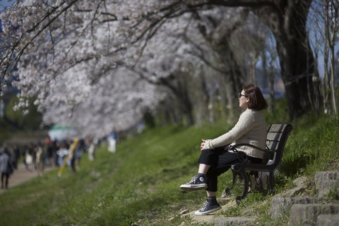 A woman sitting on a park bench looking off into the distance