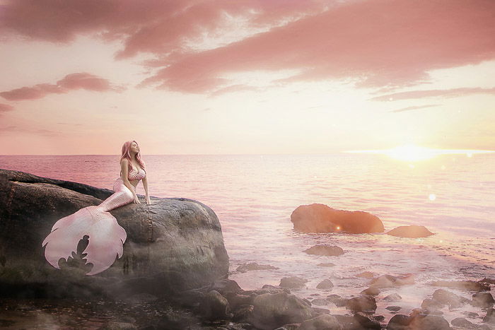 Dreamy boudoir self portrait of a female model posing in a mermaid tail by the sea