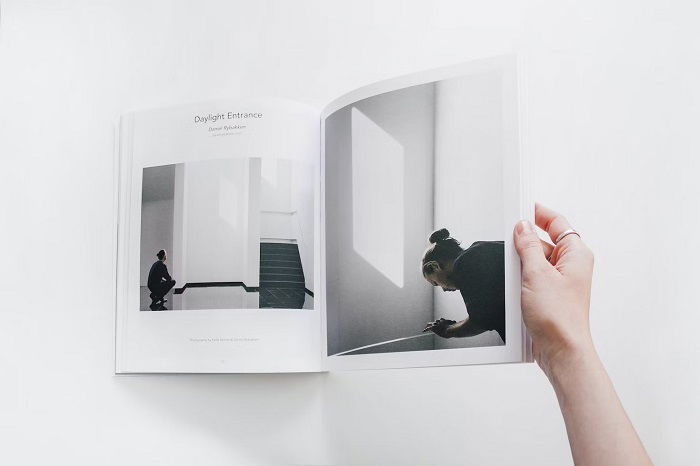 Overhead shot of a woman's hand flipping through a magazine on a white table