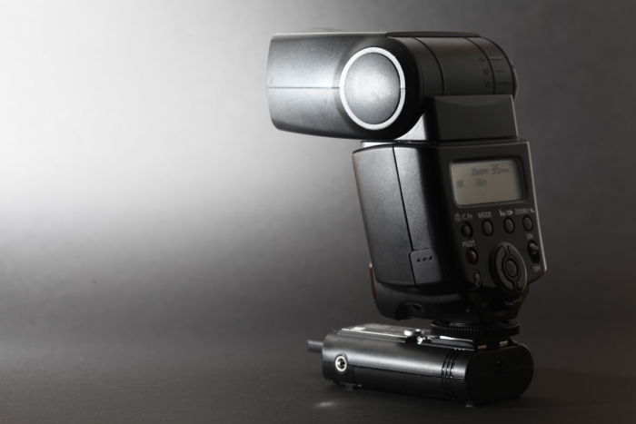 an old Canon 430EX II fires a flash at a black background - best camera flash 