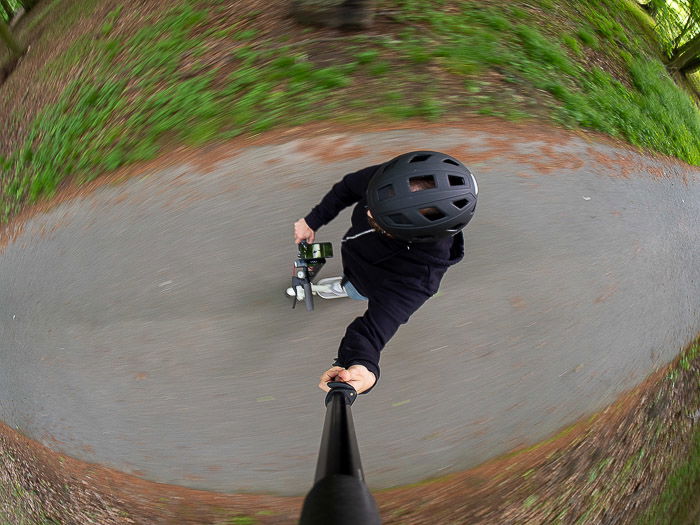 A fisheye lens selfie taken while riding an electric kick scooter in the forest.