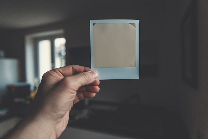 A persons hand holding a ruined polaroid photo