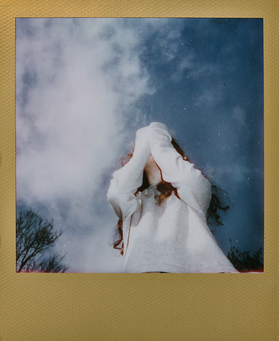 Instant photography portrait of a female model against a sky backdrop