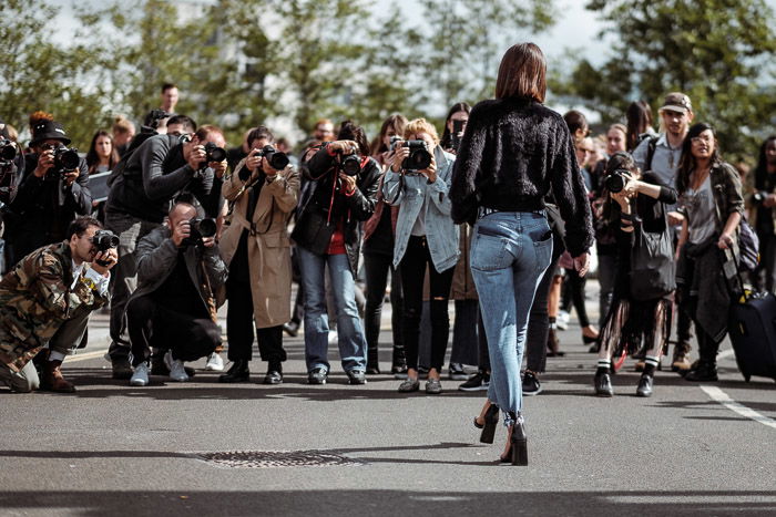 A group of photographers shooting a fashion portrait of a female model outdoors 