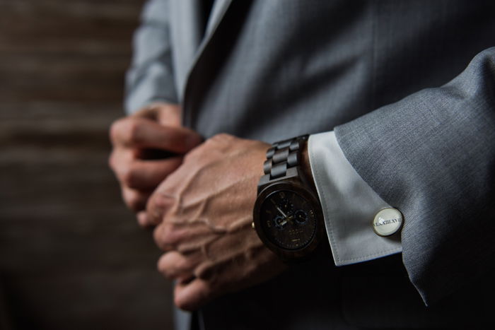 a close up wedding portrait of the groom buttoning his jacket - wedding photography business tips