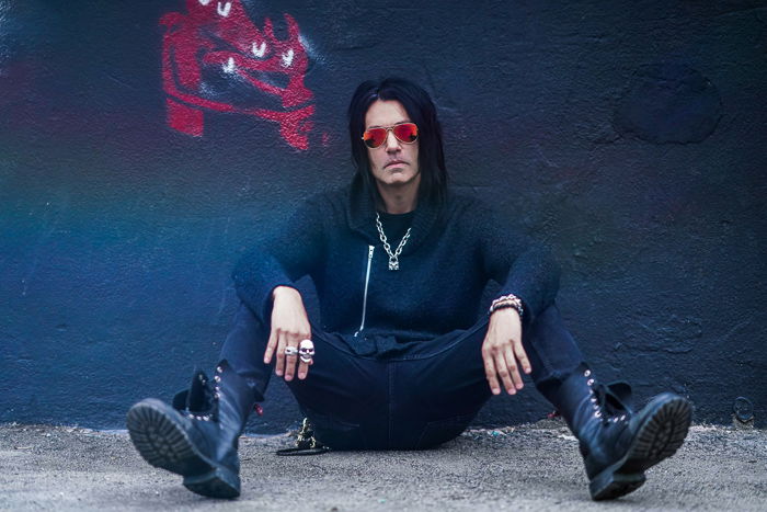 Atmospheric portrait of a male model posing moodily by a dark wall