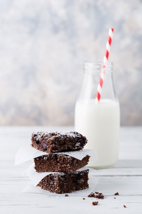 food photo of chocolate brownies in front of a bottle of milk 