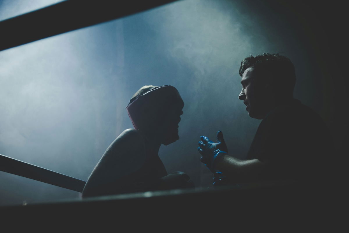 A silhouette of a boxer and referee through the ring ropes as an example of boxing photography