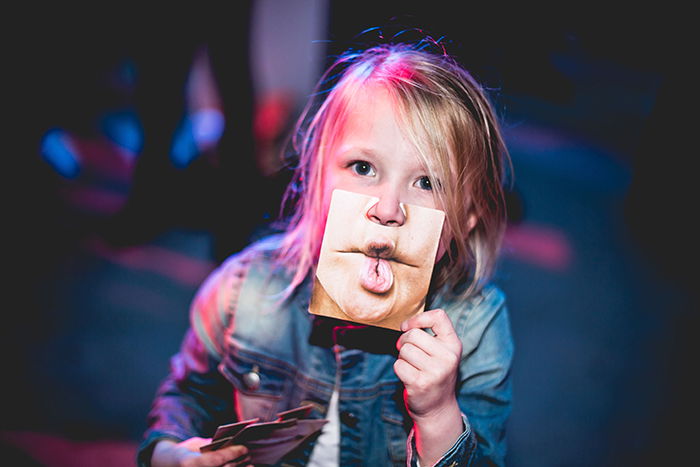 A funny photography portrait of a child holding a photo of a funny mouth to their own