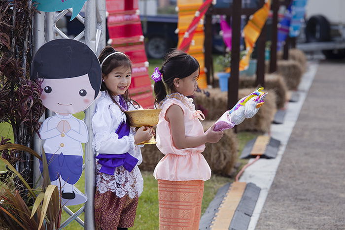 candid street photo of two little girls holding festival objects