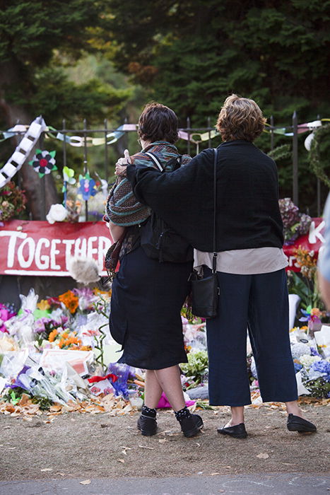 candid street photo of two women comforting each other by a memorial