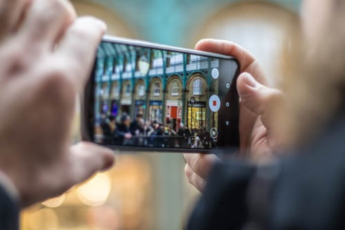 A person's hands holding a phone camera to take a picture