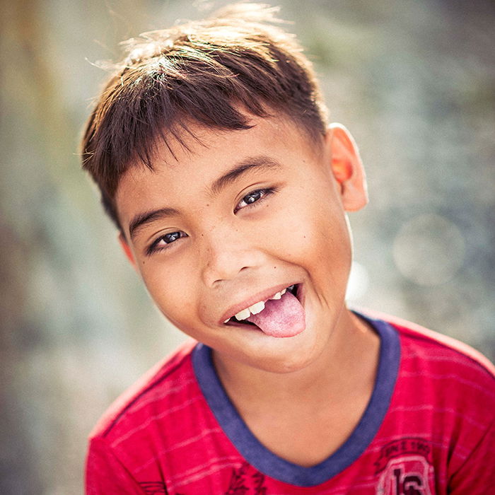 a square portrait minimalist portrait of a young boy making a funny face