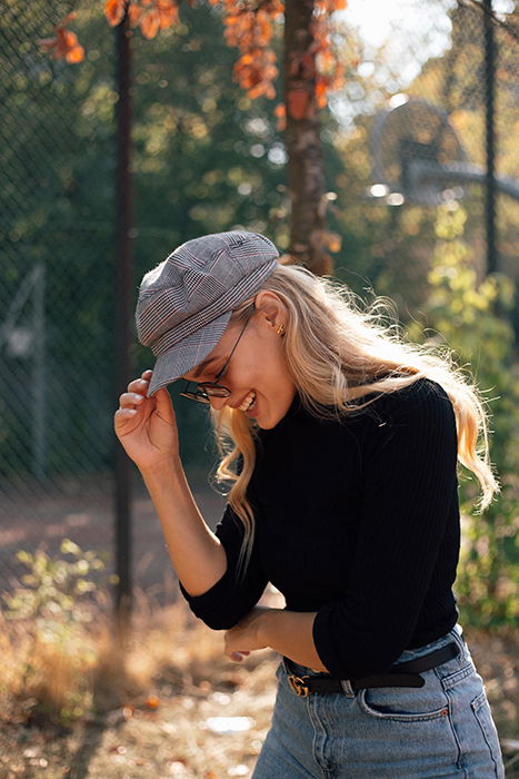 a minimalist portrait of a female model laughing outdoors