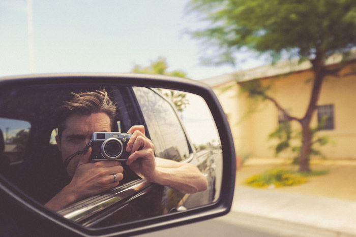 the reflection of a photographer in a car side mirror - symbolism in photography