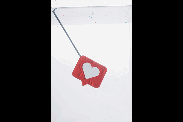 A knitting needle attached to a heart icon submerged to shoot colorful paint in water photography