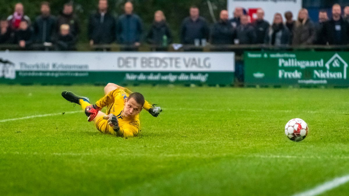 A ball going past a goalkeeper as an example of soccer photography